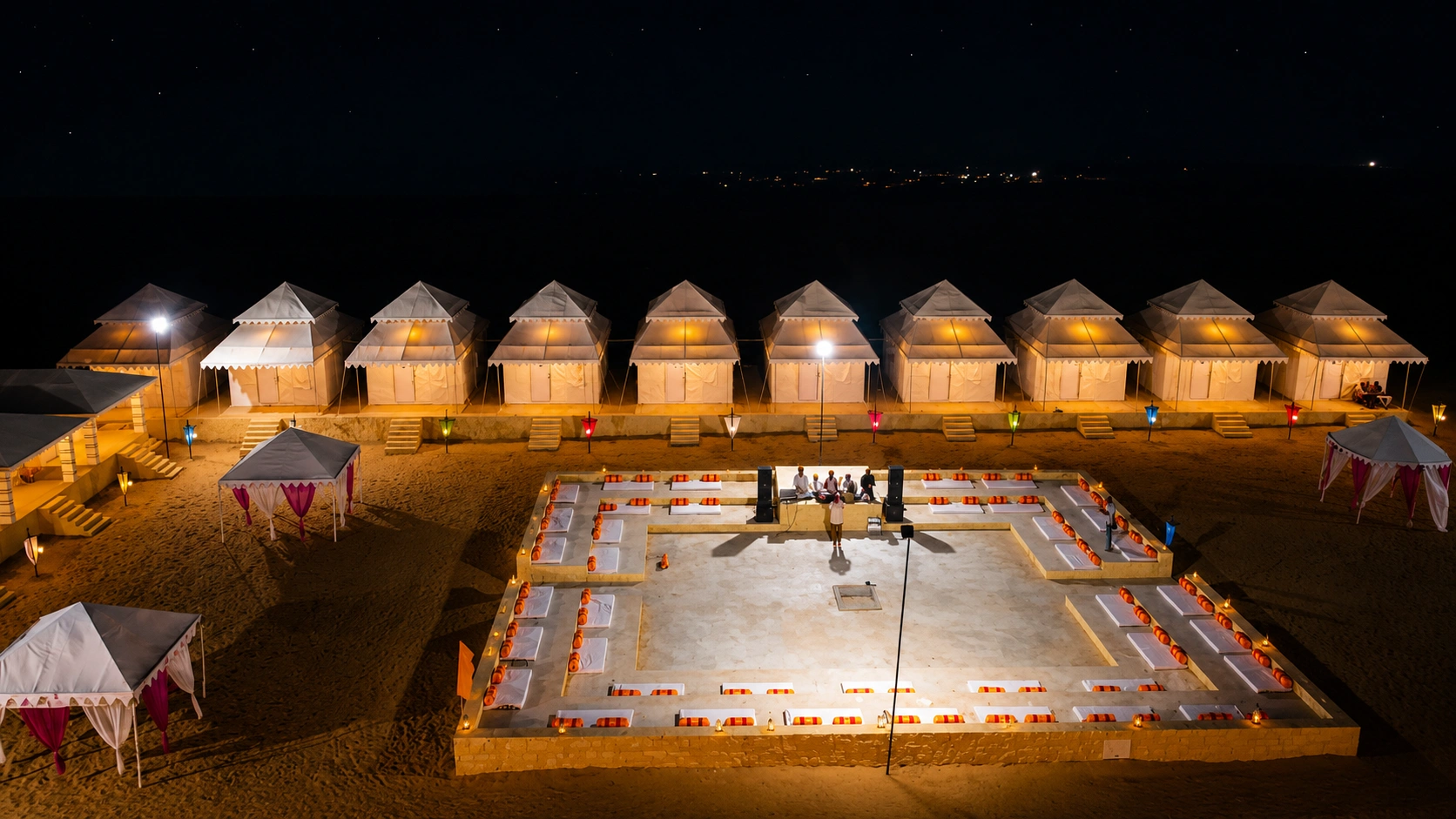 Aerial view of the desert camp glowing under a starry sky